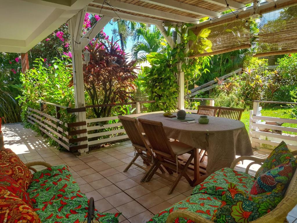 un patio con mesa, sillas y plantas en Appartement Papay dans Villa Fleurs des Iles, en Le Vauclin