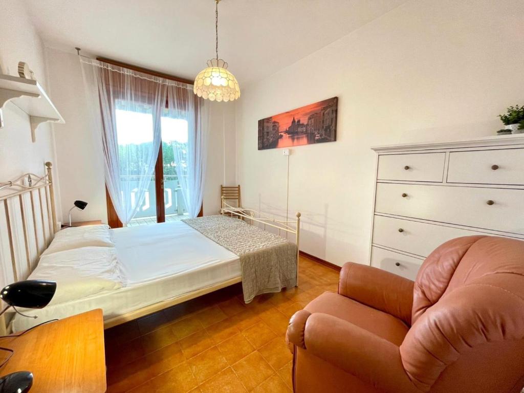 a bedroom with a bed and a chair and a dresser at Bright wide flat, 130m from the beach with shared pool in Porto Santa Margherita di Caorle