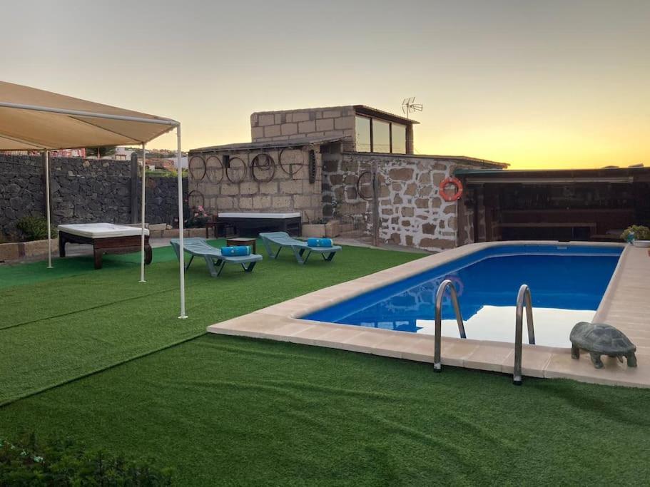 a backyard with a swimming pool and green grass at F tamaide in San Miguel de Abona