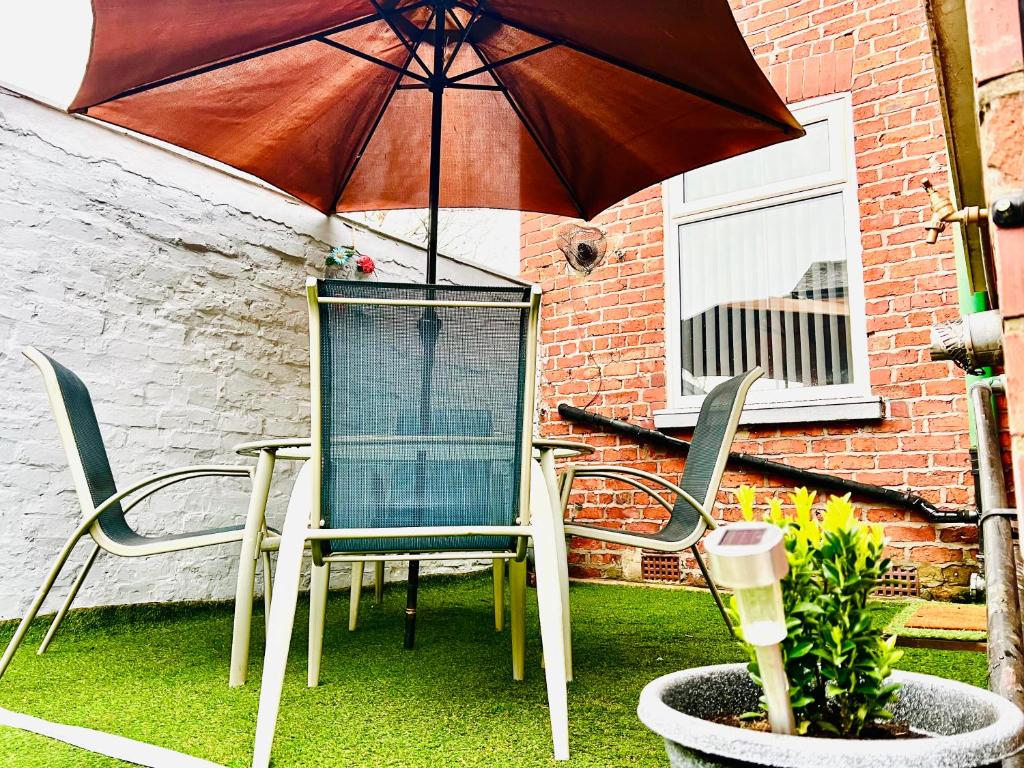 um pátio com uma mesa, cadeiras e um guarda-sol em 3 Bedroom House Near Manchester City centre em Manchester