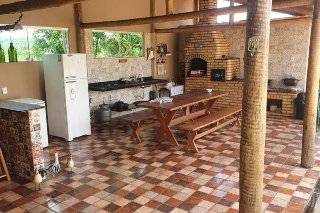 eine große Küche mit einem Tisch und einem Kühlschrank in der Unterkunft Sítio confortável a 90km de BH in Paraopeba