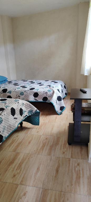 um quarto com duas camas e uma mesa num quarto em El tío lucho em Las Lajas