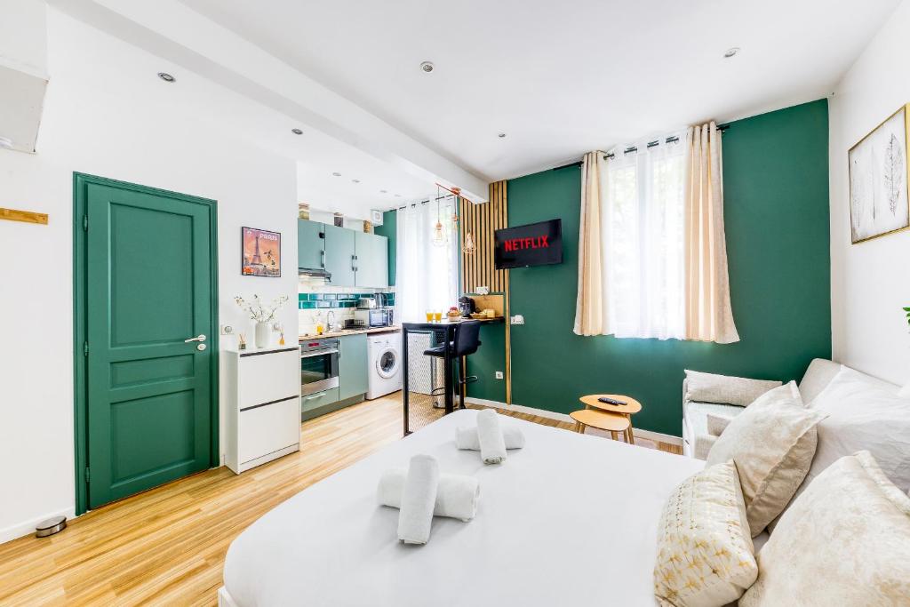 ein Wohnzimmer mit einem weißen Sofa und einer grünen Wand in der Unterkunft Le Central Green Studio Parisien Cosy Proche Métro in Clichy