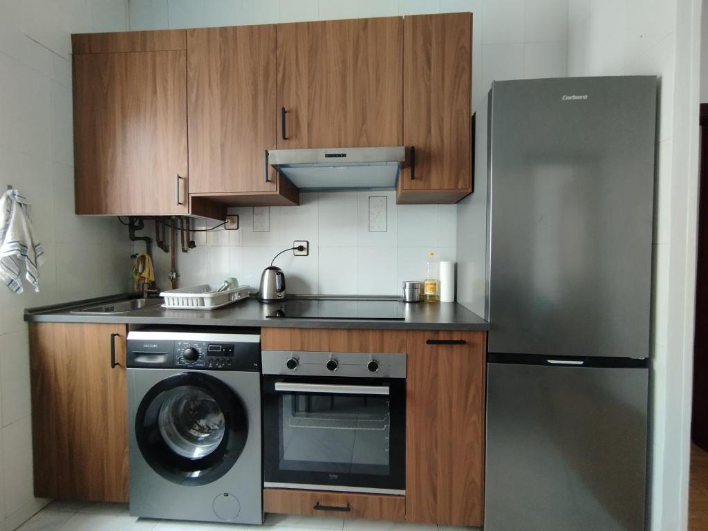 una cucina con frigorifero in acciaio inox e lavastoviglie di Apartamento en Silla del Rey a Oviedo