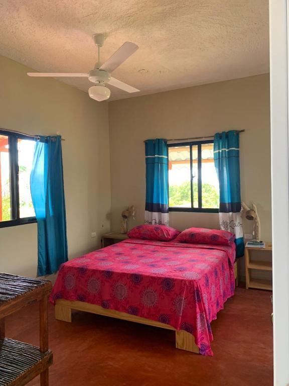 a bedroom with a red bed with blue curtains at Palma Real 1 in Madama