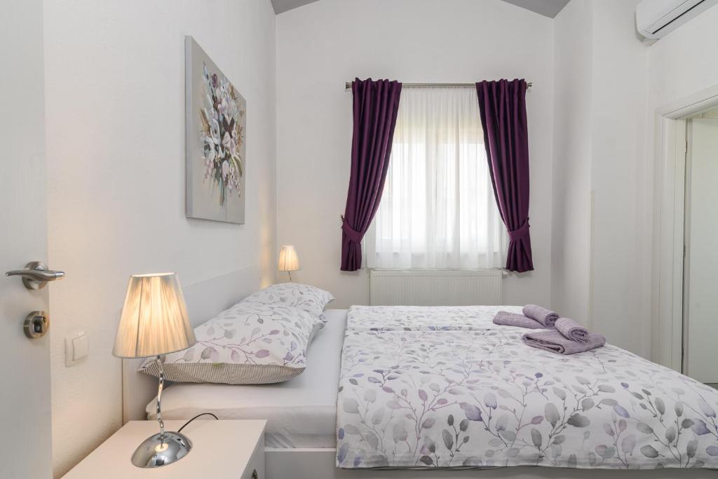 een witte slaapkamer met een bed en een raam bij Rooms Anna in Trogir