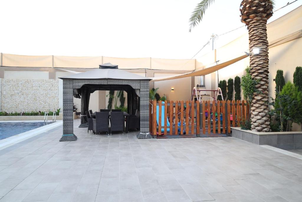 a patio with an umbrella and a fence at Waves Chalet in Al Mazār