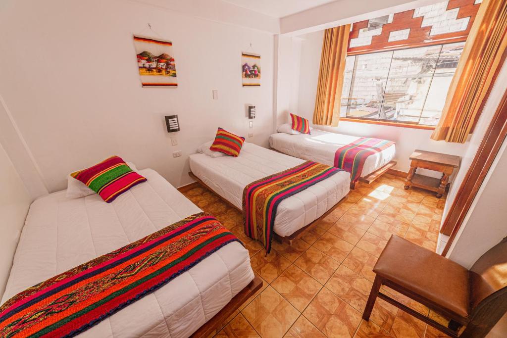 Habitación con 3 camas y ventana en Sacred Inka House, en Machu Picchu