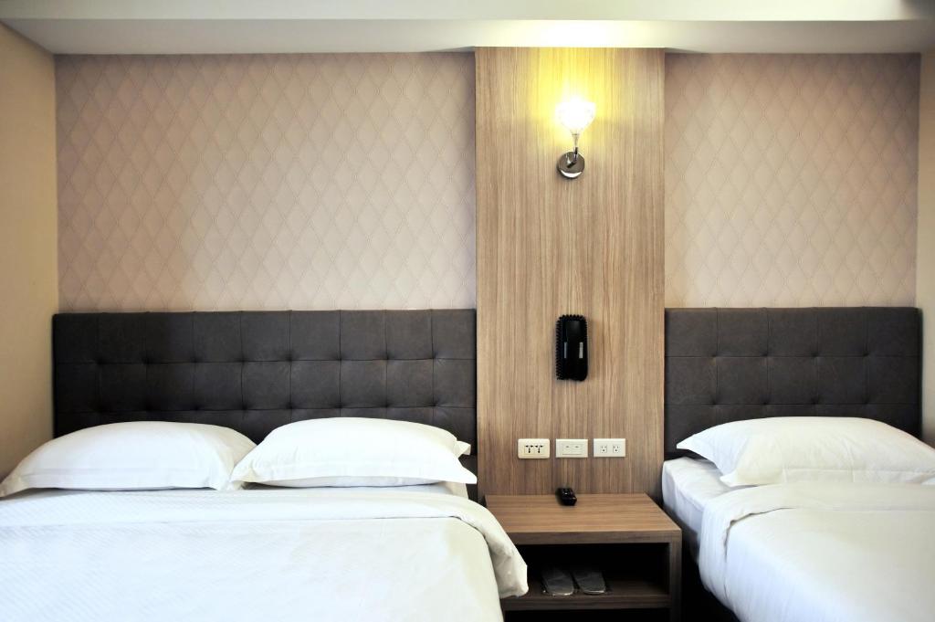 two beds in a hotel room with white pillows at The Riverside Hotel International in Kaohsiung