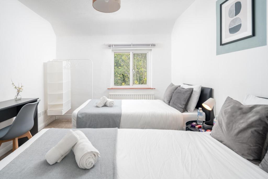 a bedroom with two beds and a desk and a window at Prime Living in Guildford