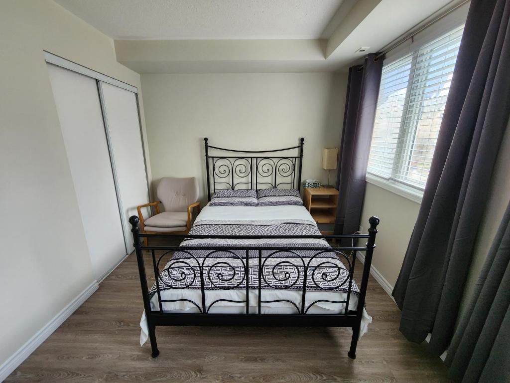 a bedroom with a bed and a chair and a window at Scarborough Townhouse in Toronto