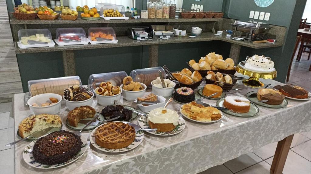 una mesa llena de diferentes tipos de pasteles y repostería en Hotel Cambirela, en Palhoça