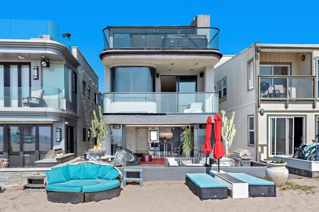 3 Story Oceanfront Home with Jacuzzi in Newport Beach on the Sand! في شاطئ نيوبورت: منزل كبير أمامه أريكة زرقاء