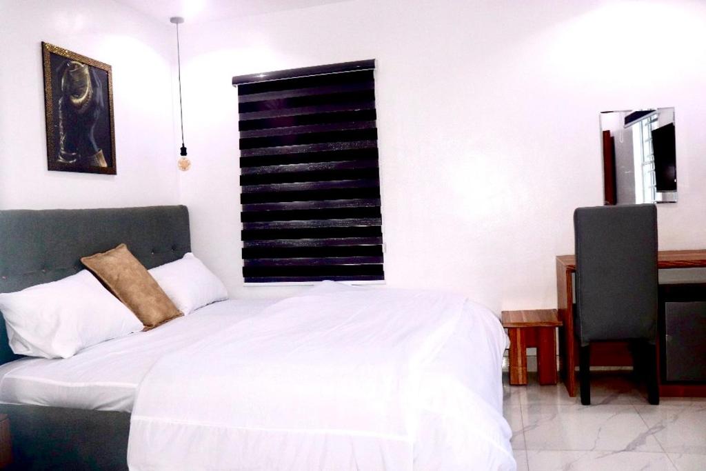 um quarto com uma cama branca e uma secretária em Ge-Mart Hotels and Suites em Lagos