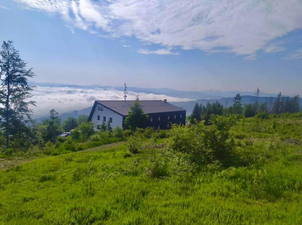 una casa en la cima de una colina con césped verde en Horský hotel Kozubová en Dolní Lomná