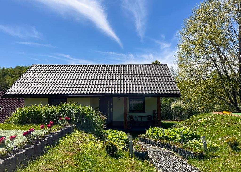 a house with a garden in front of it at Przytulny Domek z Banią in Brzozowa