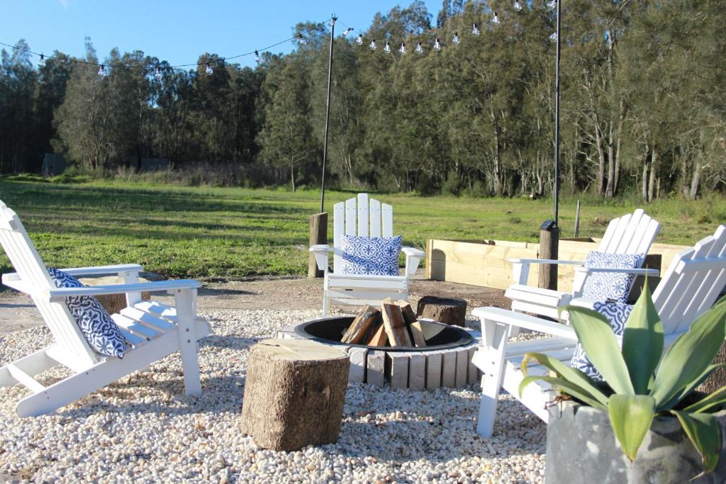 drie stoelen en een vuurplaats in een tuin bij The Ranch - Coastal Farmhouse midway to Newcastle Airport and Beaches in Salt Ash