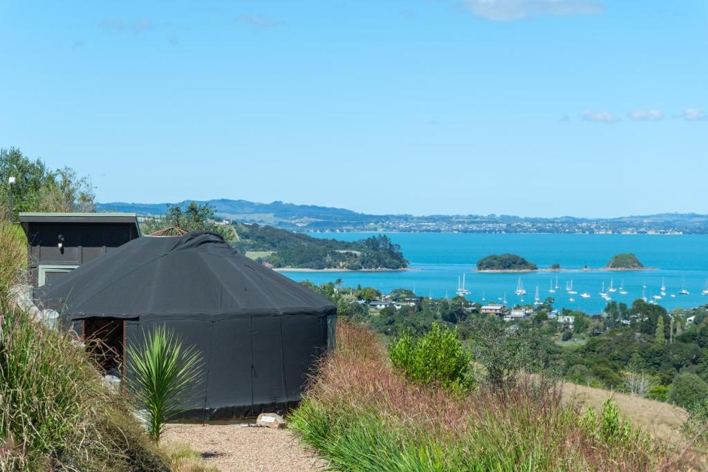 ein schwarzes Zelt auf einem Hügel mit Seeblick in der Unterkunft Awaawa - Rangi Yurt in Palm Beach