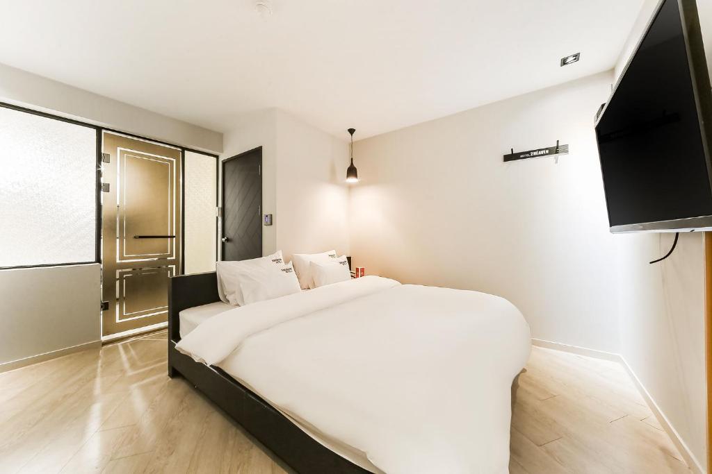 2 Heaven Hotel Songdo في بوسان: غرفة نوم بسرير ابيض وتلفزيون
