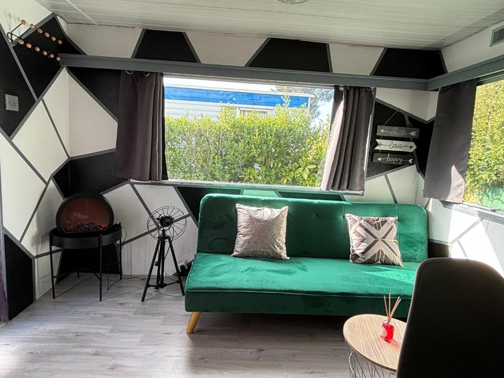 zieloną kanapę w pokoju z oknem w obiekcie Mobil-home w mieście Brêmes