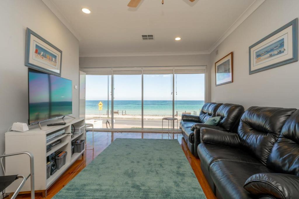 a living room with a leather couch and a television at Brighton Beachfront Sanctuary - Retro Coastal Charm in Brighton