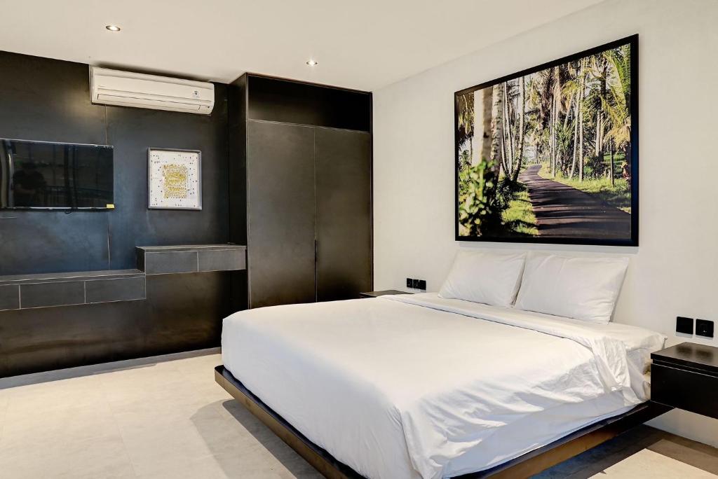 um quarto com uma cama branca e uma grande imagem na parede em Onyx em Canggu