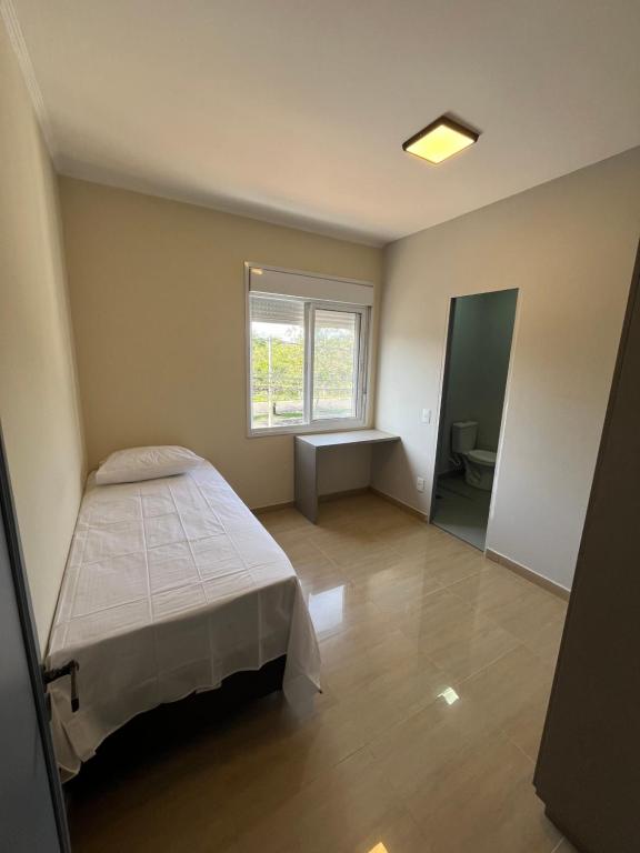 a small bedroom with a bed and a window at Astor Hostel in Campinas