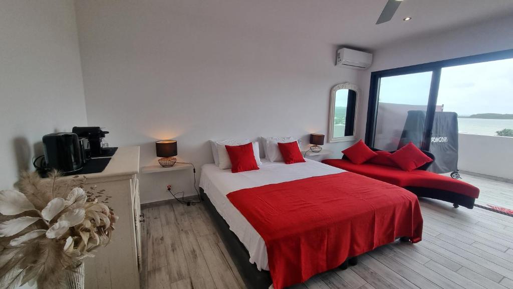 um quarto com uma cama grande e almofadas vermelhas em VUE SUR MER em Noumea