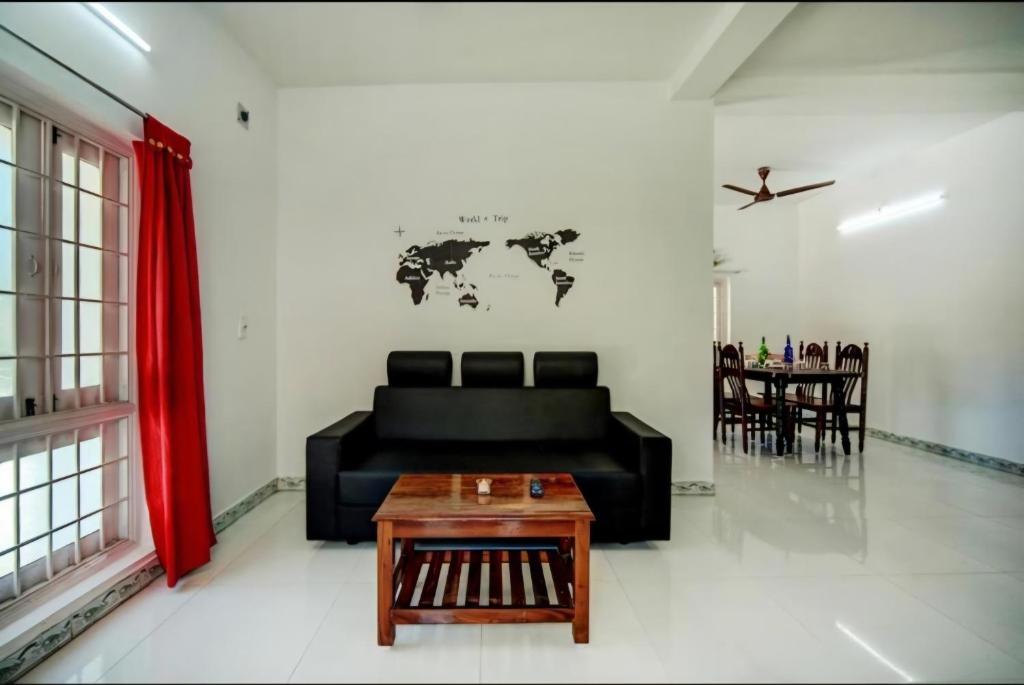 sala de estar con sofá negro y mesa en Stay in serinity beach 2bhk villa., en Pondicherry