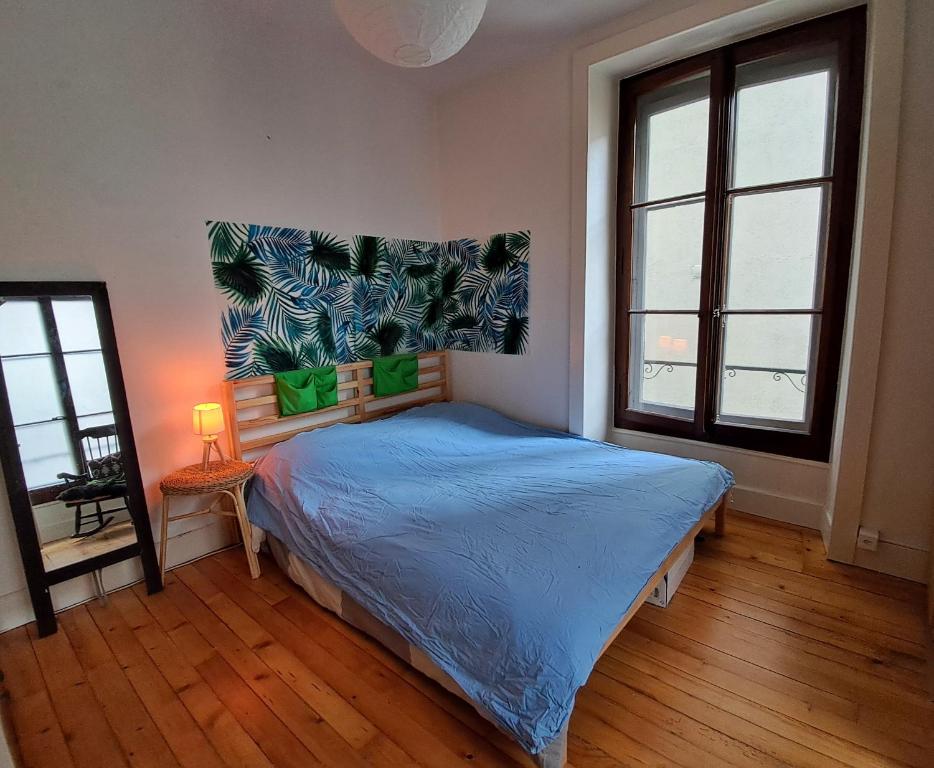 una camera da letto con un letto con un piumone blu e due finestre di À côté du lac a Vevey
