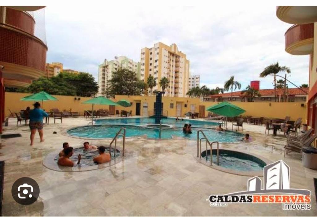 a group of people in a swimming pool at Apartamento Mobiliado com Área de Lazer in Caldas Novas