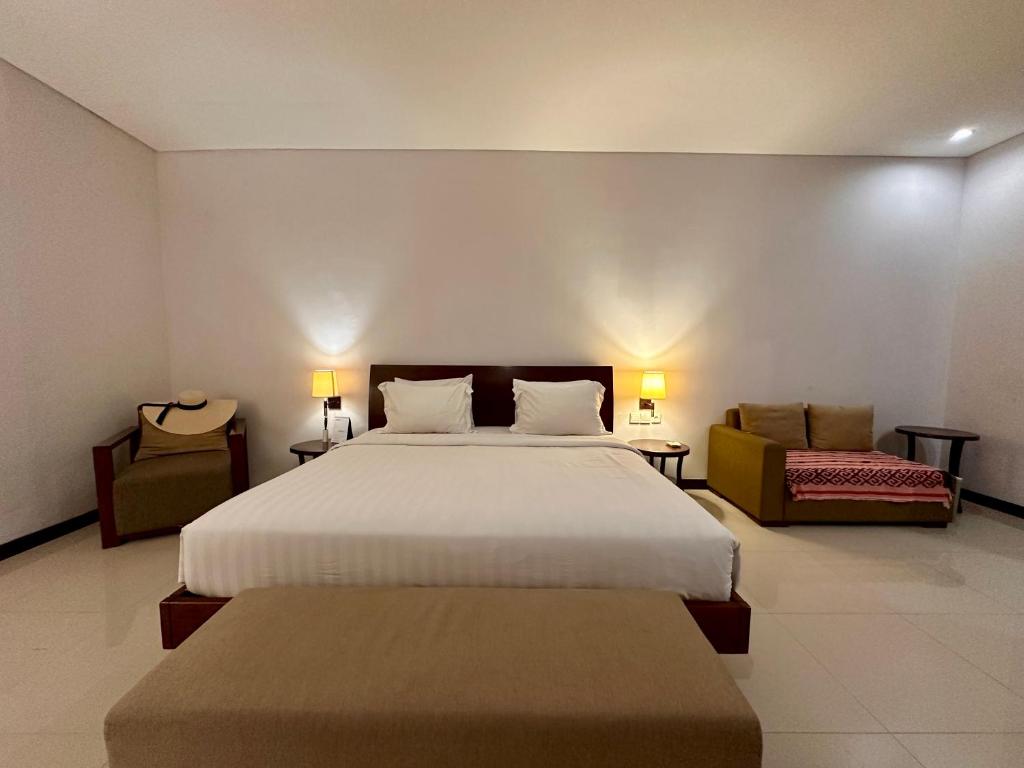 a bedroom with a large bed and two chairs at Karuna Uppala Villa Umalas in Canggu