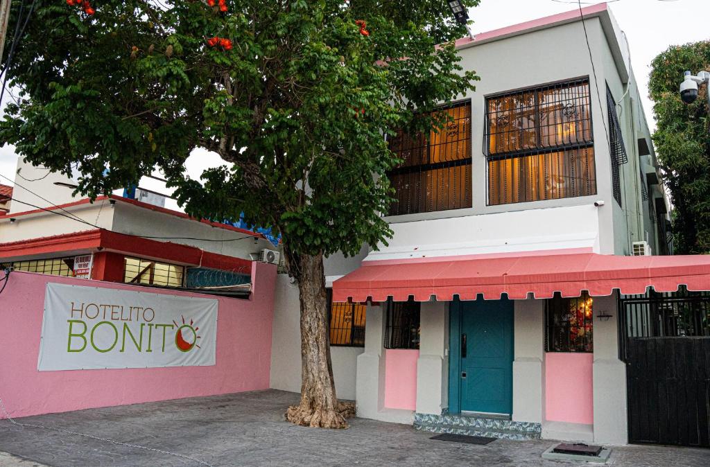 un bâtiment rose et blanc avec un arbre devant dans l'établissement Hotelito Bonito Eli & Edw, à Saint-Domingue