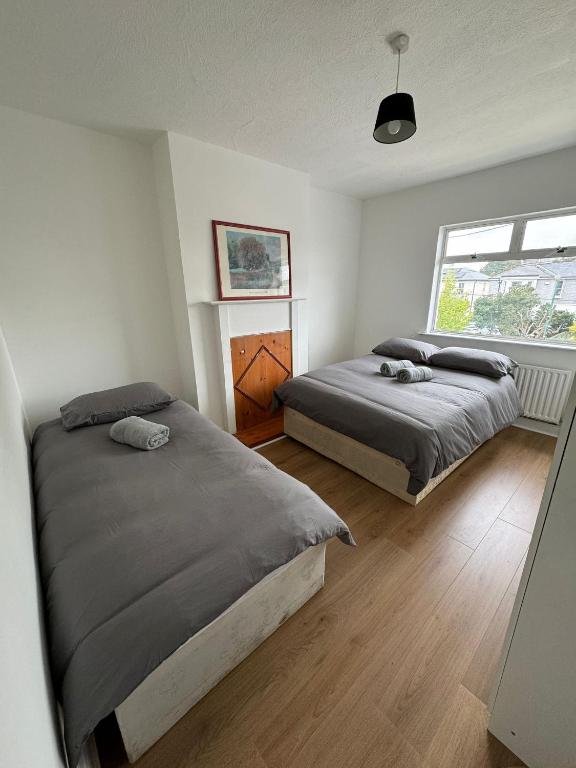 um quarto com 2 camas e uma janela em Nice Triple Room at 2 Iveragh Rd-7 em Dublin