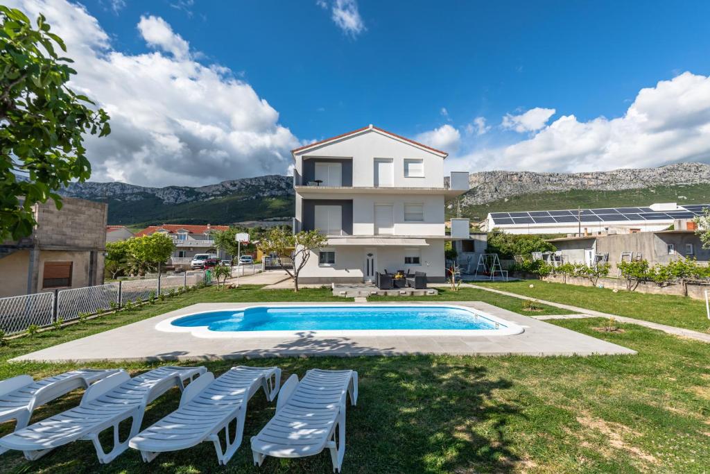 ein Haus mit einem Pool und Stühlen in der Unterkunft Family friendly house with 3 rooms,big pool and grill near Split in Kaštel Sućurac