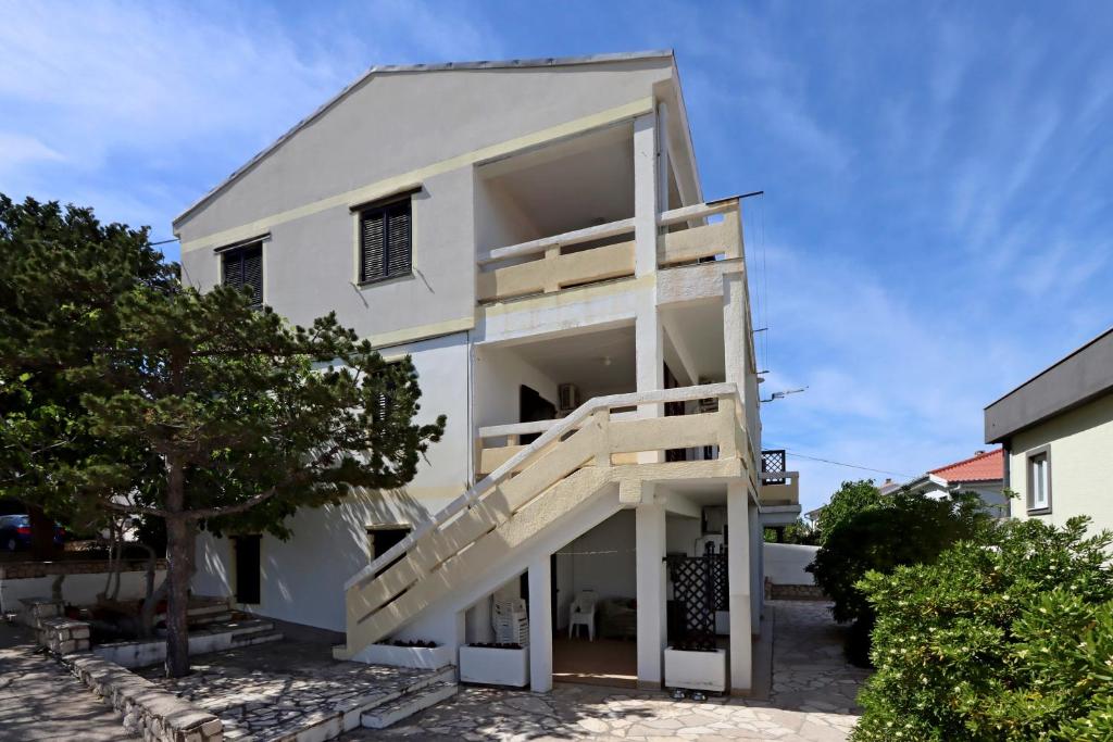 Una casa blanca con escaleras al frente. en Apartments with parking space Pag - 18325, en Pag