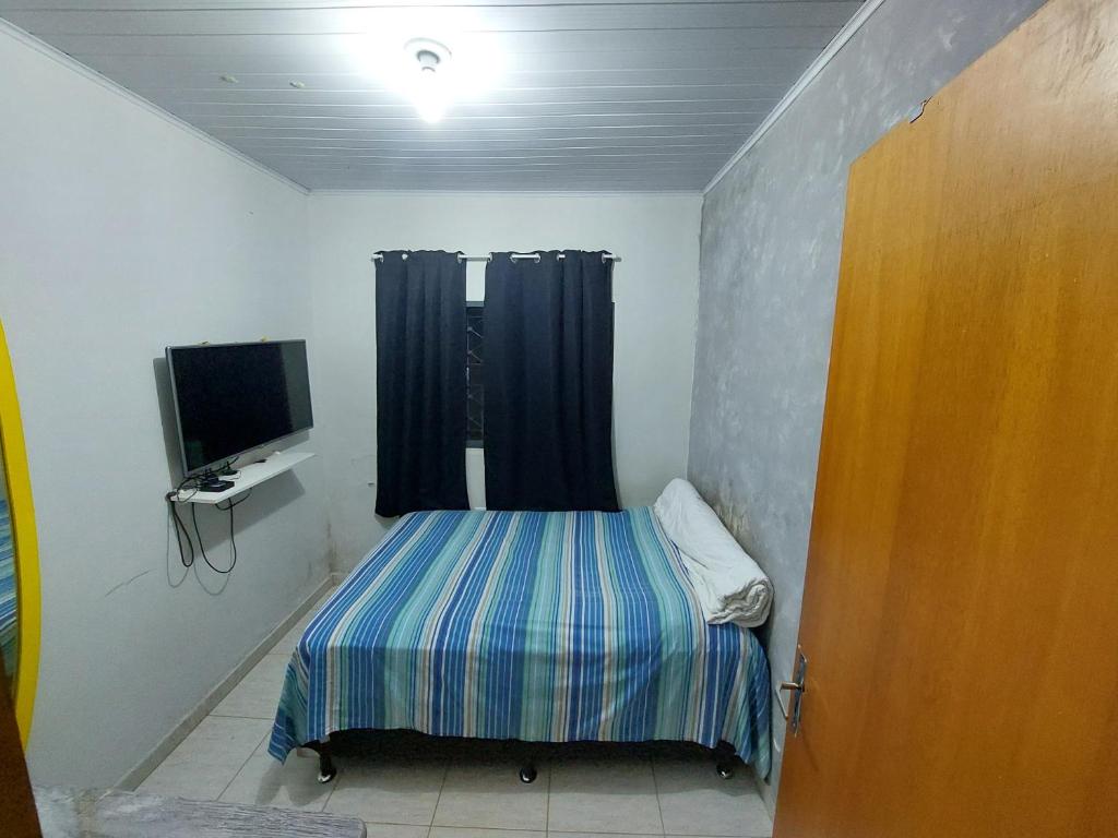 a small room with a bed and a television at Quarto para Agrishow in Ribeirão Preto