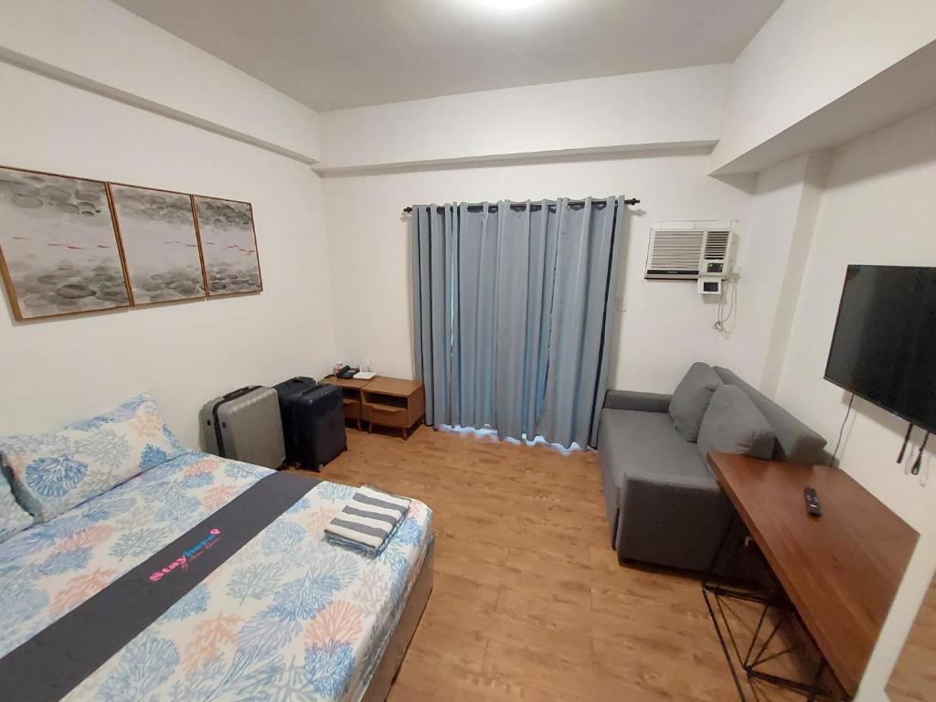 a bedroom with a bed and a couch and a television at ANIA CONDO STAY in Mactan