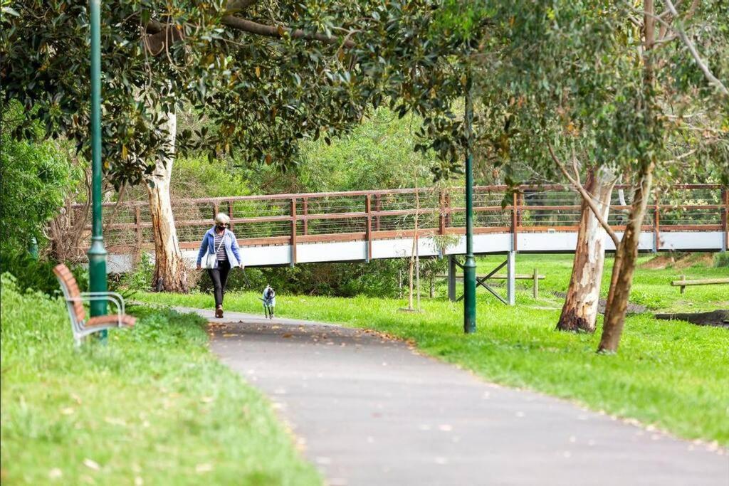 une femme marchant un chien sur un chemin dans un parc dans l'établissement Stunning Cosy 1BR Apartment in heart of Elwood, à Melbourne