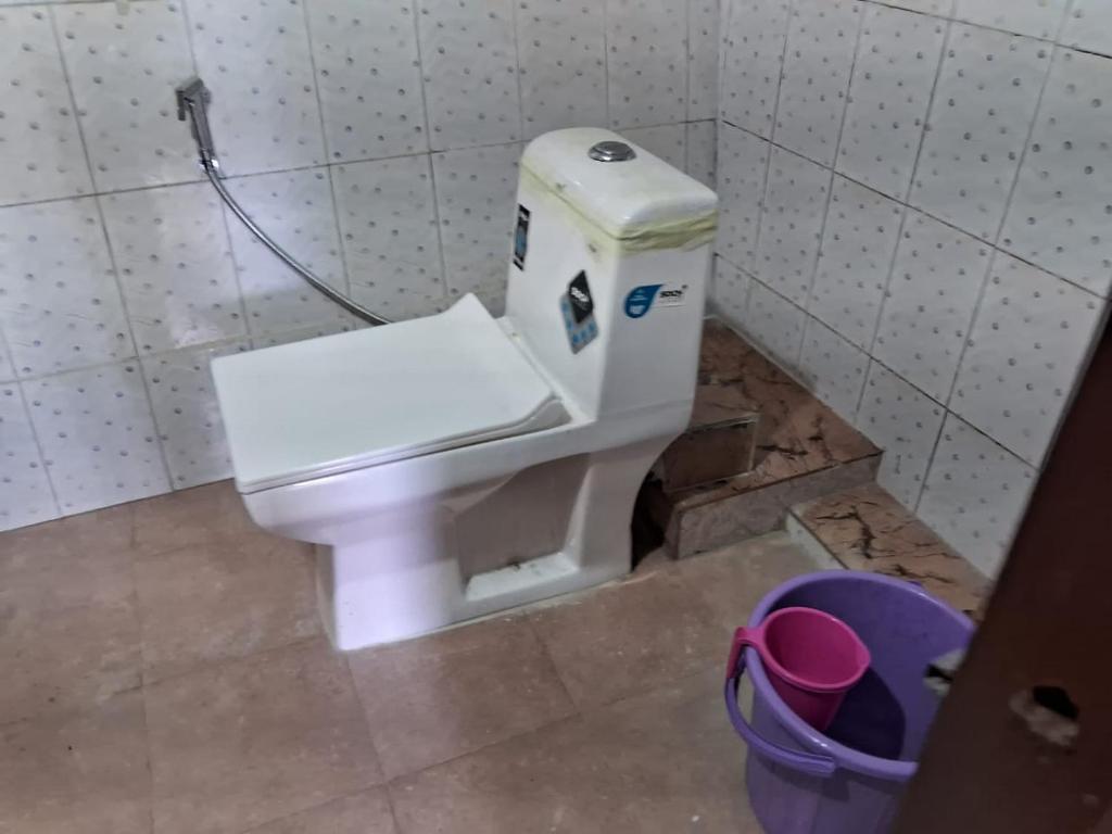 um WC branco numa casa de banho com um balde em Kharga Homestay em Darjeeling