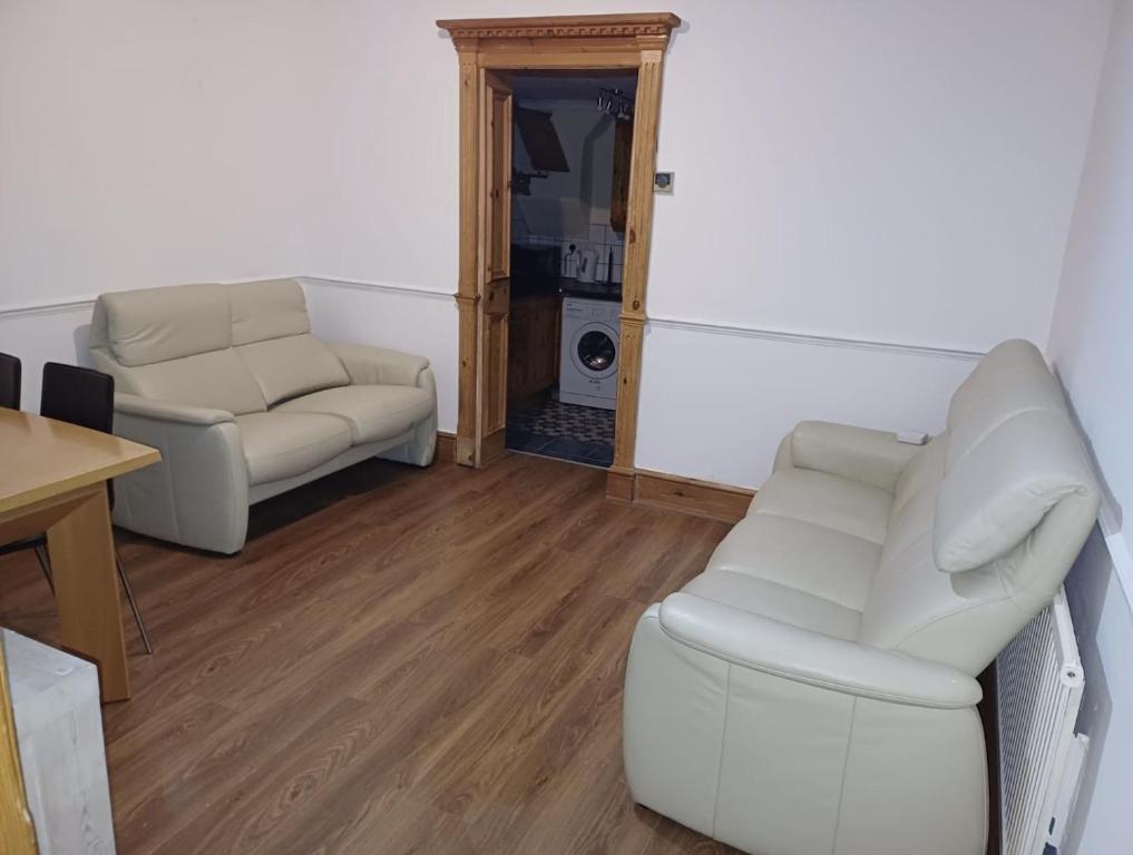 - un salon avec deux chaises blanches et une table dans l'établissement NKY CRYSTAL 4 Bed House Apartment, à Londres