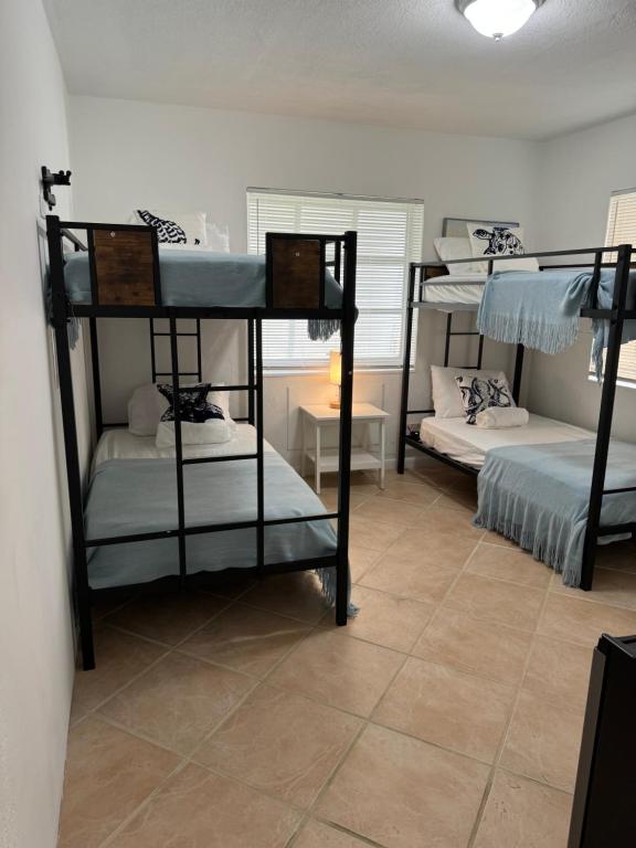 Zimmer mit 3 Etagenbetten in einem Zimmer in der Unterkunft Hostel Beds & Sheets FLL AIRPORT in Dania Beach