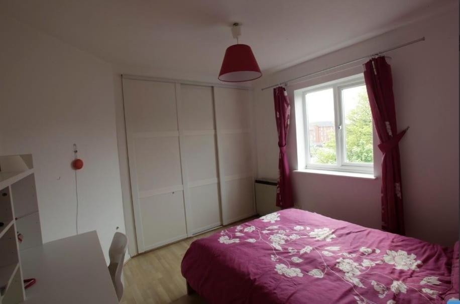 ein Schlafzimmer mit einem rosa Bett und einem Fenster in der Unterkunft Waterstone in London