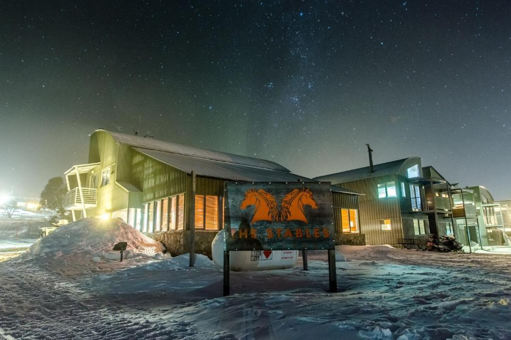 a building with a sign in the snow at night at Lodge Chalet 28 - The Stables Perisher in Perisher Valley