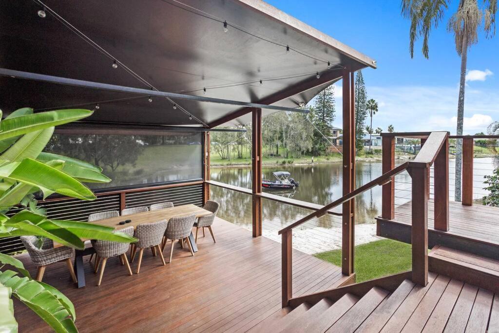 a wooden deck with a table and chairs on the water at Lakefront Living in Burleigh in Gold Coast