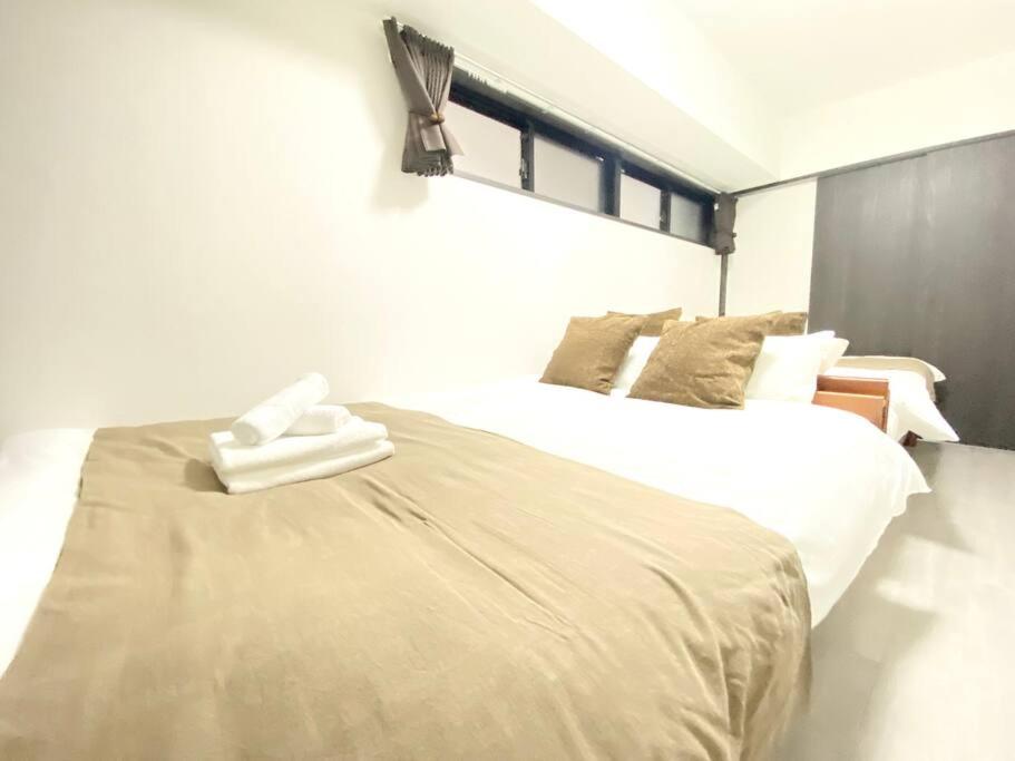 um quarto com uma grande cama branca e 2 almofadas em アネックス日本橋東201 em Osaka