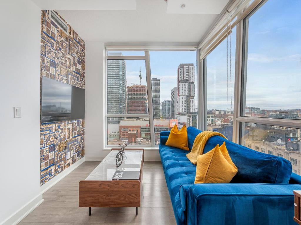 uma sala de estar com um sofá azul e janelas grandes em Boutique Vista Two Bedroom Suite - Toronto's Entertainment District em Toronto