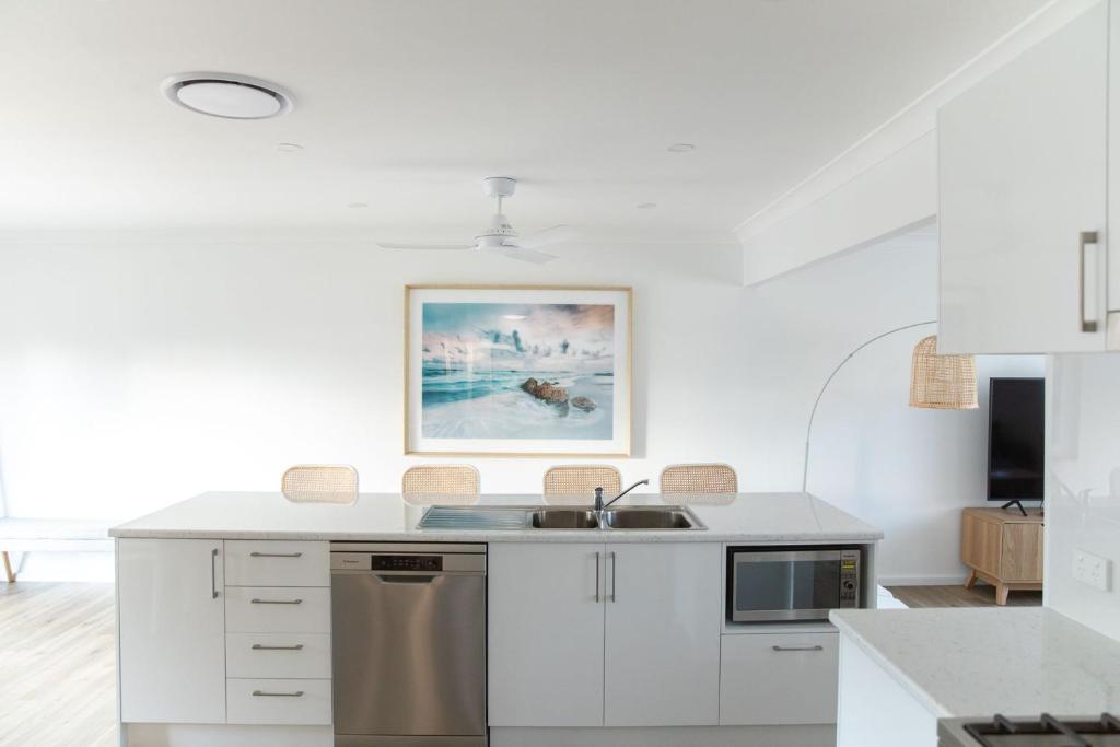 Una cocina con gabinetes blancos y un fregadero. en Beach Haven, en Vincentia