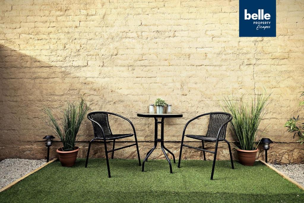 two chairs and a table with plants in front of a wall at 2 BR Apartment in Melbourne Street - North Adelaide in Adelaide