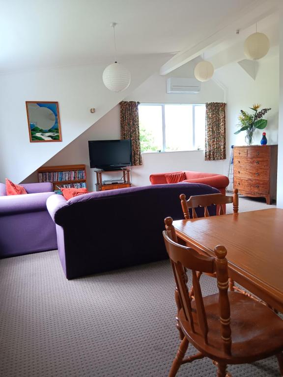 ein Wohnzimmer mit einem Sofa und einem Tisch in der Unterkunft Purple Hen Country Lodge in Katikati